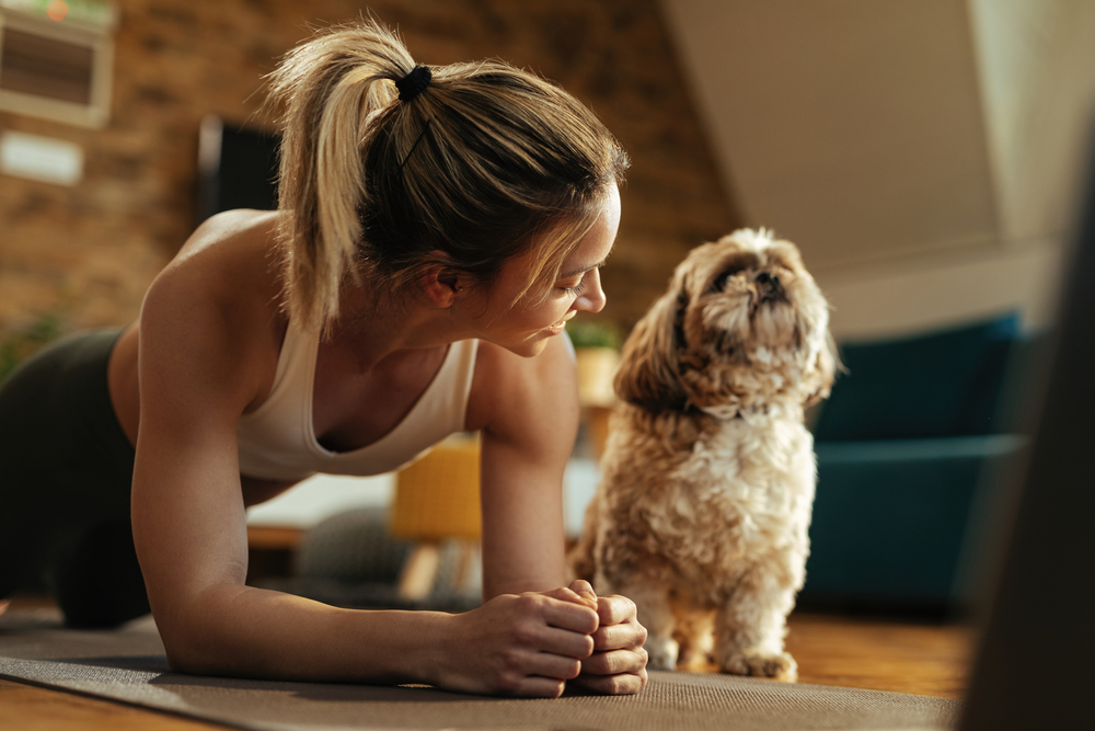 Woman doing yoga at home with dog