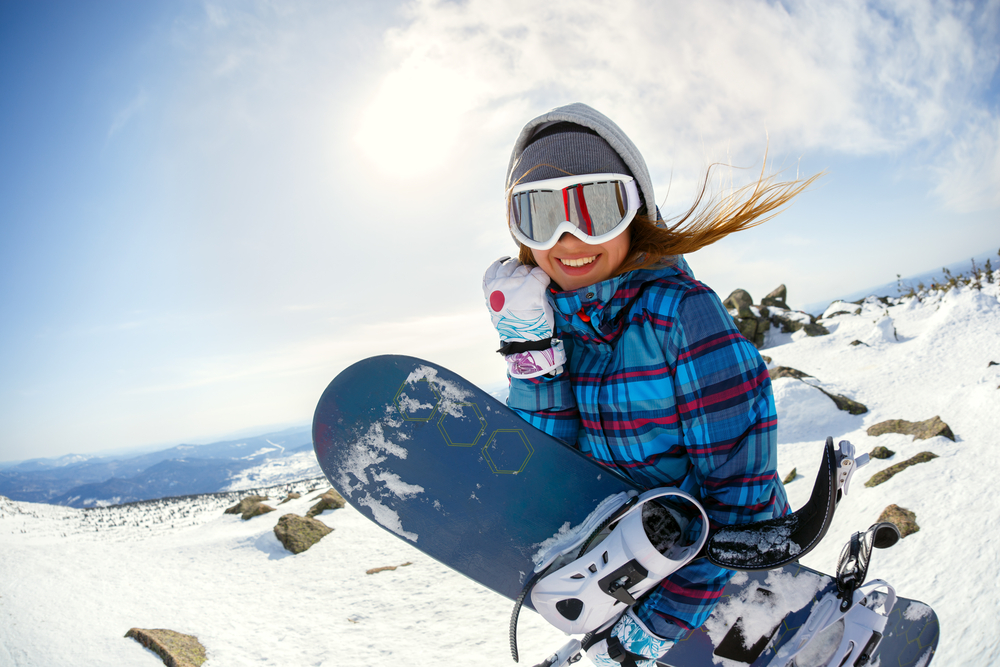 Female snowboarder smiling holding snowboard.