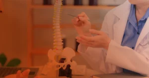 physician pointing to an area of a model spine