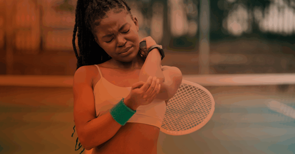 woman playing tennis and holding elbow in pain