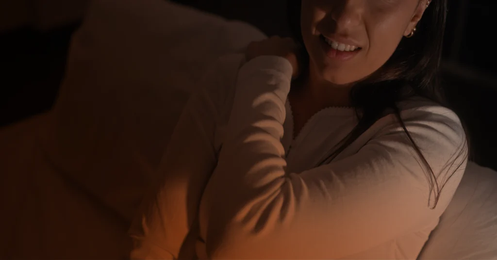 A woman grabs her shoulder in pain.