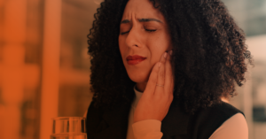 A woman with pain in her jaw rubs her face.
